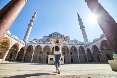 Şapkalı mutlu çekici kadın turist, İstanbul 'daki Süleyman camisinin avlusunda poz veriyor. Din ve seyahat kavramı.