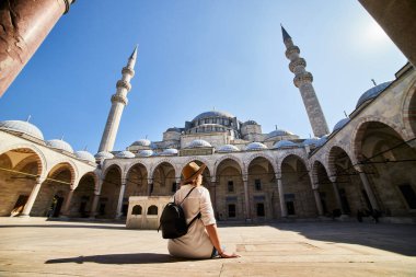 Şapkalı mutlu çekici kadın turist, İstanbul 'daki Süleyman camisinin avlusunda poz veriyor. Din ve seyahat kavramı.