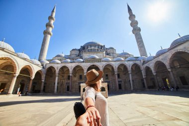 Beni takip edin. Şapkalı bir kadın turist, arkadaşını İstanbul, İstanbul 'daki Türk camisine götürüyor. Seyahat ve din kavramı.