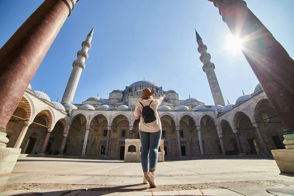 Şapkalı mutlu çekici kadın turist, İstanbul 'daki Süleyman camisinin avlusunda poz veriyor. Din ve seyahat kavramı.