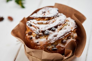 Beyaz ahşap arka planda kuru üzüm ve krema ile süslenmiş Paskalya pastası geleneksel Kulich ve Paska kutlamaya hazır.