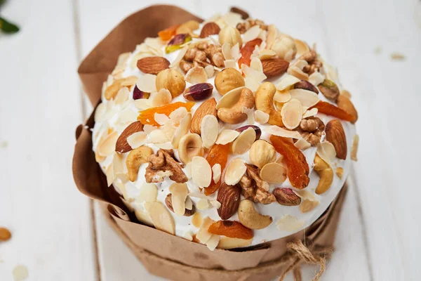 Easter cake decorated by nuts and dried fruits on white wooden background, Traditional Kulich, Paska  ready for celebration