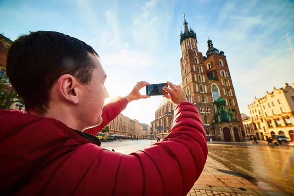 波兰克拉科夫日出时分 一位年轻人正在市场广场拍摄著名的圣玛丽大教堂的照片 — 图库照片