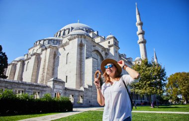 Şapkalı mutlu çekici kadın turist, İstanbul 'daki Süleyman Camii' nin arka planında Simitci 'yi (susamlı yuvarlak bir simit) tutuyor. Din ve seyahat kavramı.
