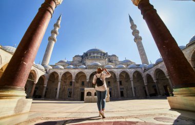 Şapkalı mutlu çekici kadın turist, İstanbul 'daki Süleyman camisinin avlusunda poz veriyor. Din ve seyahat kavramı.