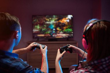 Çılgın, oyuncu bir çiftin portresi, Playstation 'da oyun oynayan oyuncular kanepede oturuyor, konsol Gamepad' i ellerinde tutuyorlar, Xbox hayranları. Evde dinlenmek, iyi hafta sonları.