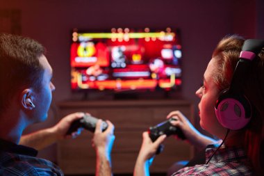 Çılgın, oyuncu bir çiftin portresi, Playstation 'da oyun oynayan oyuncular kanepede oturuyor, konsol Gamepad' i ellerinde tutuyorlar, Xbox hayranları. Evde dinlenmek, iyi hafta sonları.