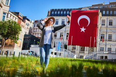 Çekici genç kadın turist, İstanbul 'daki Beyoğlu Belediye Binası' nda Türk bayrağının arka planında selfie çekiyor