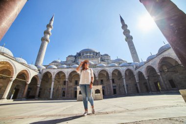 Şapkalı mutlu çekici kadın turist, İstanbul 'daki Süleyman camisinin avlusunda poz veriyor. Din ve seyahat kavramı.