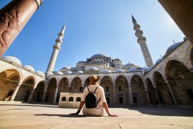 Şapkalı mutlu çekici kadın turist, İstanbul 'daki Süleyman camisinin avlusunda poz veriyor. Din ve seyahat kavramı.