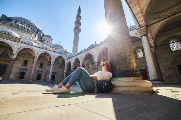 Şapkalı mutlu çekici kadın turist, İstanbul 'daki Süleyman camisinin avlusunda poz veriyor. Din ve seyahat kavramı.