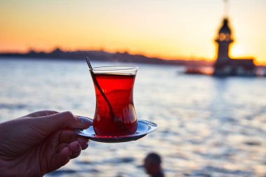 İstanbul, Türkiye 'nin sembolü Leander' ın Kulesi olarak da bilinen ünlü Maiden 's Tower (Kiz Kulesi) ile günbatımının arka planında el altında geleneksel Türk çayı (armudu).