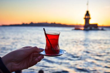 İstanbul, Türkiye 'nin sembolü Leander' ın Kulesi olarak da bilinen ünlü Maiden 's Tower (Kiz Kulesi) ile günbatımının arka planında el altında geleneksel Türk çayı (armudu).