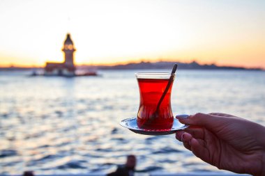 İstanbul, Türkiye 'nin sembolü Leander' ın Kulesi olarak da bilinen ünlü Maiden 's Tower (Kiz Kulesi) ile günbatımının arka planında el altında geleneksel Türk çayı (armudu).