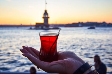 İstanbul, Türkiye 'nin sembolü Leander' ın Kulesi olarak da bilinen ünlü Maiden 's Tower (Kiz Kulesi) ile günbatımının arka planında el altında geleneksel Türk çayı (armudu).