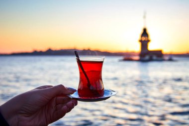 İstanbul, Türkiye 'nin sembolü Leander' ın Kulesi olarak da bilinen ünlü Maiden 's Tower (Kiz Kulesi) ile günbatımının arka planında el altında geleneksel Türk çayı (armudu).