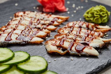 Füme yılan balığı dilimlenmiş fileto taze salatalık, zencefil turşusu ve slate tabakta wasabi.