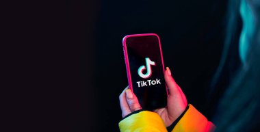 Vinnitsa, Ukrayna - 08 Nisan 2020.Tik tok reklam konsepti. Elinde akıllı bir telefonla poz veren genç bir kız siyah arka planda selfie çekiyor. TIK TOK internette popüler bir sosyal ağ.. 