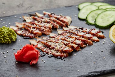 Füme yılan balığı dilimlenmiş fileto taze salatalık, zencefil turşusu ve slate tabakta wasabi.