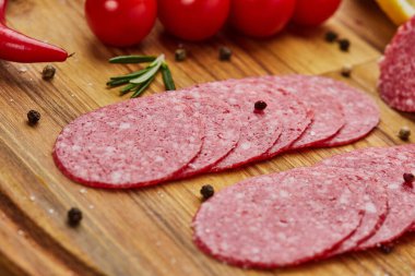 Geleneksel ince dilimlenmiş salam ahşap bir kesme tahtasında baharatlar, marul, avokado ve domateslerle birlikte. Soğuk et tabağı