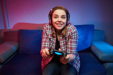 Playstation 'da video oyunu oynayan çılgın oyuncunun portresi kanepede oturmuş, konsol oyun platformunu elinde tutuyor, Xbox hayranları. Evde dinlenmek, iyi hafta sonları.