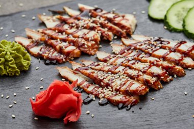 Füme yılan balığı dilimlenmiş fileto taze salatalık, zencefil turşusu ve slate tabakta wasabi.