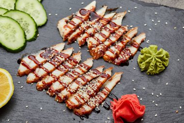 Füme yılan balığı dilimlenmiş fileto taze salatalık, zencefil turşusu ve slate tabakta wasabi.