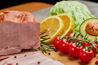 Baharatlı jambon, marul, avokado ve ahşap kesim tahtasında domates. Eski et tabağı Taze prosciutto