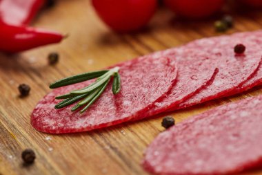 Geleneksel ince dilimlenmiş salam ahşap bir kesme tahtasında baharatlar, marul, avokado ve domateslerle birlikte. Soğuk et tabağı