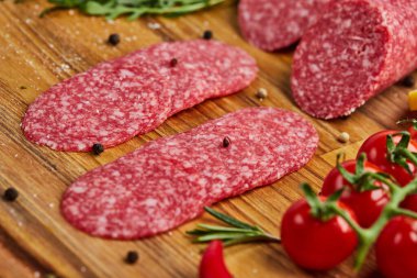 Geleneksel ince dilimlenmiş salam ahşap bir kesme tahtasında baharatlar, marul, avokado ve domateslerle birlikte. Soğuk et tabağı