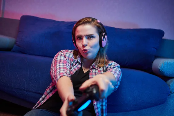 Portrait of crazy playful Gamer , girl enjoying Playing Video Games indoors sitting on the sofa, holding Console Gamepad in hands. Resting At Home, have a great Weekend