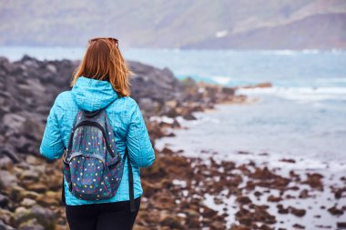 Sırt çantalı kadın turist rıhtımda durup Puerto de la Cruz 'da okyanusu izliyor, Kanarya Adaları, İspanya
