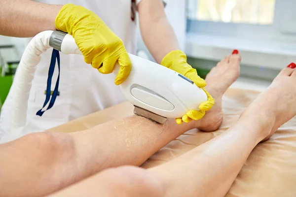 Young woman remove hair on legs at cosmetology clinic. Laser Hair Removal, photoepilation, body and skin care concept.