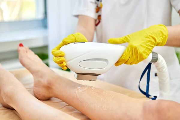 Young woman remove hair on legs at cosmetology clinic. Laser Hair Removal, photoepilation, body and skin care concept.