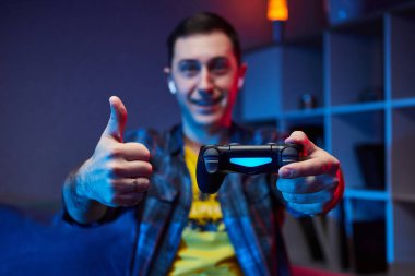 Playstation 'da video oyunu oynayan çılgın oyuncunun portresi kanepede oturmuş, konsol oyun platformunu elinde tutuyor, Xbox hayranları. Evde dinlenmek, iyi hafta sonları..