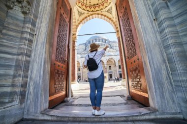 İstanbul, Türkiye - 14 Ekim 2019: İstanbul, Türkiye 'deki Süleyman camisinin avlusunda poz veren şapkalı mutlu çekici kadın turist. Din ve seyahat kavramı.