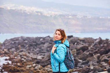 Sırt çantalı kadın turist rıhtımda durup Puerto de la Cruz 'da okyanusu izliyor, Kanarya Adaları, İspanya