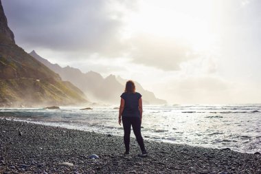 Siyah kum volkanik Beniho (Benijo) plajında duran kadın - Tenerife 'nin kuzeyinde. Kanarya Adaları. İspanya