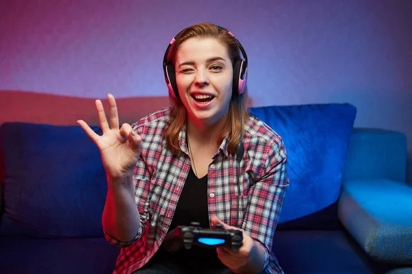 一个疯狂玩乐的游戏者的肖像 一个喜欢在室内玩电子游戏的女孩坐在沙发上 手里拿着控制台游戏垫 在家休息 度过一个愉快的周末 — 图库照片
