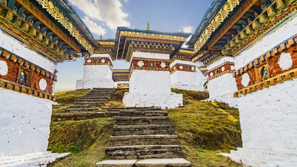 Dochula pass 108 chortens (estupas asiáticas) es el monumento en honor de los soldados butaneses en la ciudad de Timpu con el paisaje de hierba y el fondo nublado del cielo, Bután — Foto de Stock