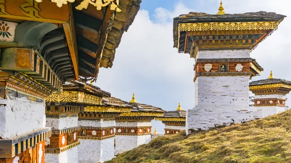 Dochula pass 108 chortens (estupas asiáticas) es el monumento en honor de los soldados butaneses en la ciudad de Timpu con el paisaje de hierba y el fondo nublado del cielo, Bután — Foto de Stock