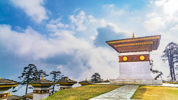Dochula pass 108 chortens (estupas asiáticas) es el monumento en honor de los soldados butaneses en la ciudad de Timpu con el paisaje de hierba y el fondo nublado del cielo, Bután — Foto de Stock