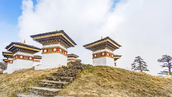 Dochula pass 108 chortens (estupas asiáticas) es el monumento en honor de los soldados butaneses en la ciudad de Timpu con el paisaje de hierba y el fondo nublado del cielo, Bután — Foto de Stock