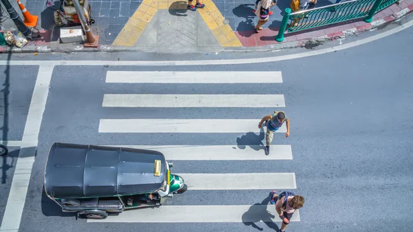 La multitud de gente ocupada de la ciudad pasa por el paso peatonal en la carretera de tráfico con el mini coche Tuktuk. Bangkok, Tailandia (Foto aérea, vista superior ) — Foto de Stock