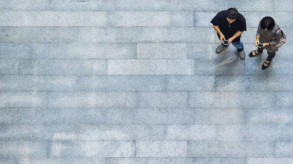 Ovanifrån grupp människor spelar och pratar med den smarta telefonen på konkreta fotgängare (Flygfoto) — Stockfoto