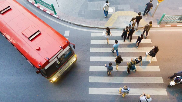 Lidé chodí přes ulici, než autobus se chystá zastavit na přechod pro chodce v pohledu shora (ortofoto). Bangkok, Thajsko. — Stock fotografie