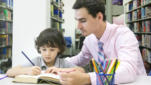 Profesor y estudiante chirld aprendizaje y dibujo en el boo de color — Foto de Stock