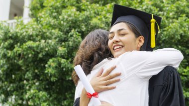 kız öğrenci mezuniyet önlük ve şapka ile sarılmak üst kutlama töreni.