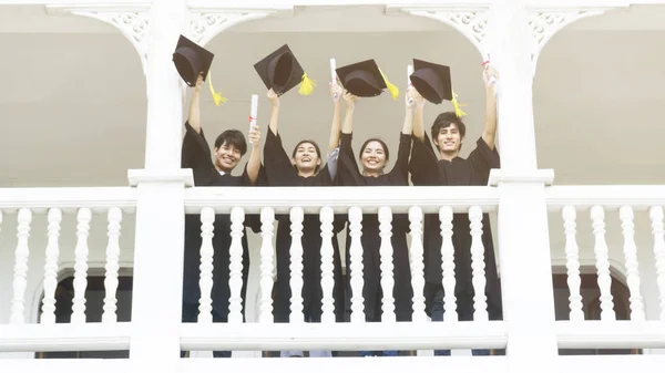 Personnes étudiants dans le sentiment de bonheur et de grâce avec les robes de remise des diplômes et casquette debout dans la ligne au couloir du bâtiment classique . — Photo