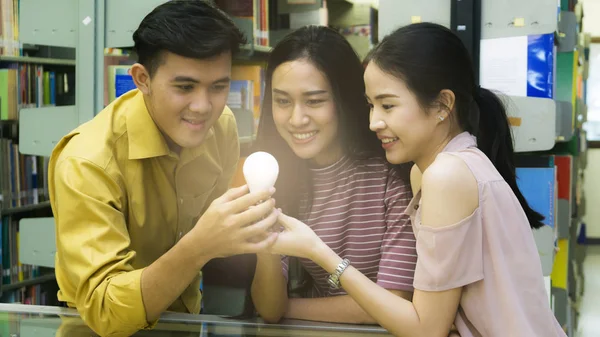 Groupe de personnes étudiants tiennent l'ampoule avec la lumière à l'intérieur et pensent quelque chose . — Photo